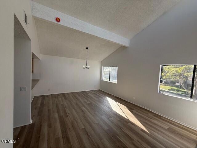 unfurnished living room with beamed ceiling, dark hardwood / wood-style flooring, and a wealth of natural light