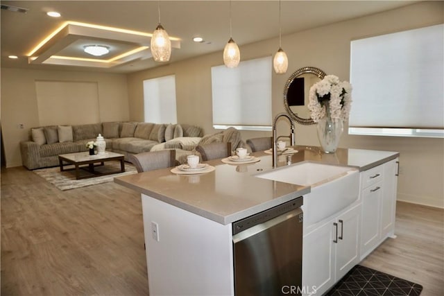 kitchen featuring sink, hanging light fixtures, stainless steel dishwasher, light hardwood / wood-style floors, and white cabinets