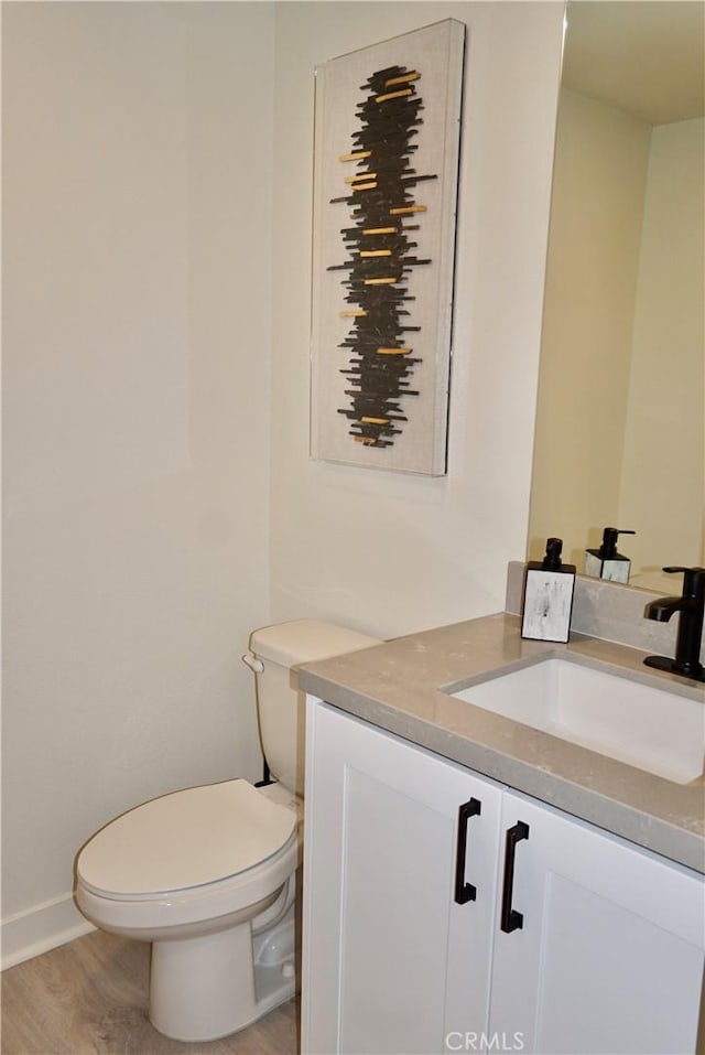 bathroom featuring wood-type flooring, vanity, and toilet