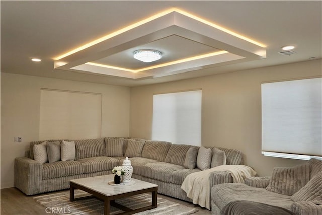 living room featuring a tray ceiling and hardwood / wood-style flooring