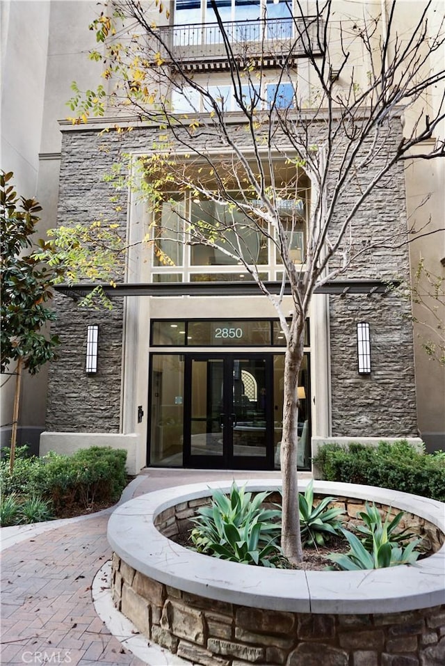 view of exterior entry with a balcony and french doors