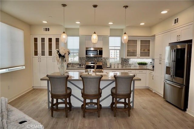 kitchen featuring white cabinets, appliances with stainless steel finishes, light wood-type flooring, and a kitchen island