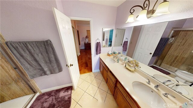 full bathroom featuring double vanity, tile patterned flooring, toilet, and a shower stall