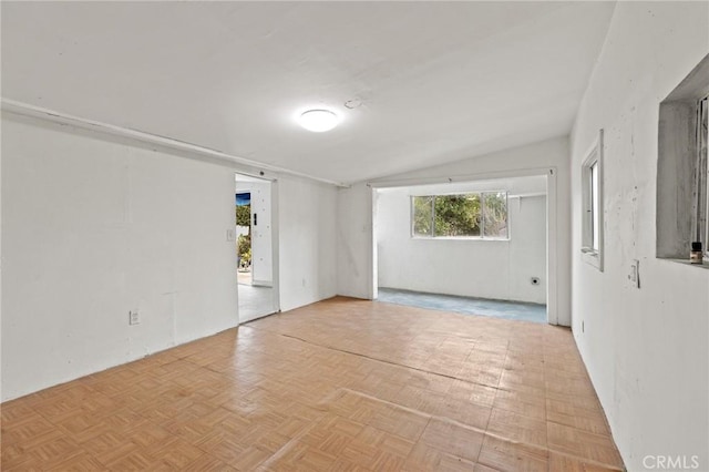 spare room with light parquet floors and vaulted ceiling