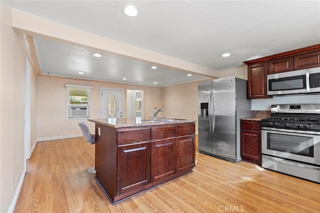 kitchen with light wood-type flooring, stainless steel appliances, a kitchen island with sink, cooling unit, and sink