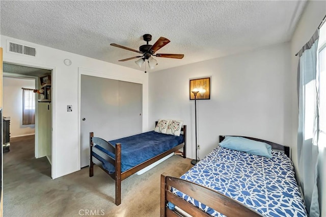 bedroom with ceiling fan, a closet, light colored carpet, and a textured ceiling