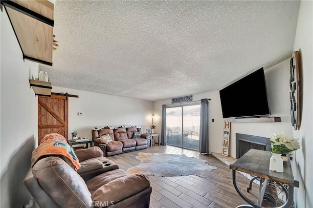 living room featuring a barn door, wood-type flooring, and a textured ceiling