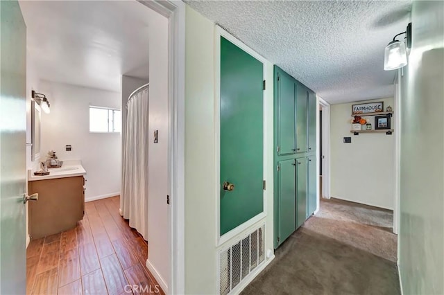 hall featuring carpet flooring, sink, and a textured ceiling