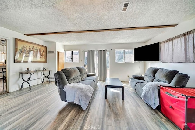 living room with hardwood / wood-style flooring, a textured ceiling, and beamed ceiling