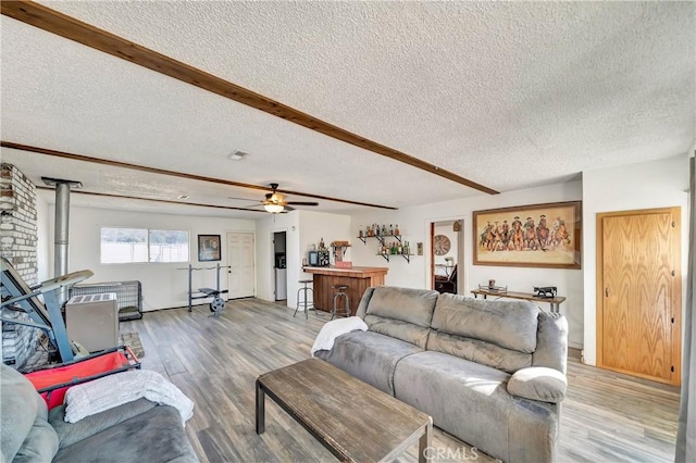 living room featuring beam ceiling, wood-type flooring, and a textured ceiling