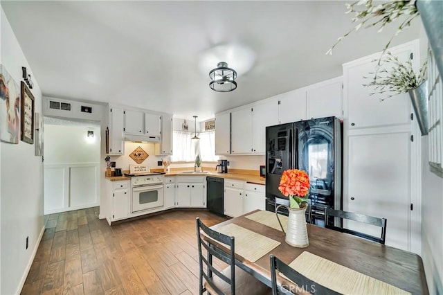 kitchen with white cabinetry, sink, wood-type flooring, decorative light fixtures, and black appliances