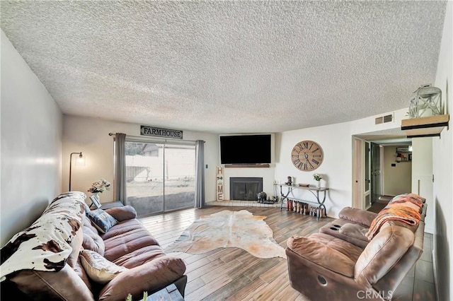 living room with a textured ceiling and light hardwood / wood-style flooring