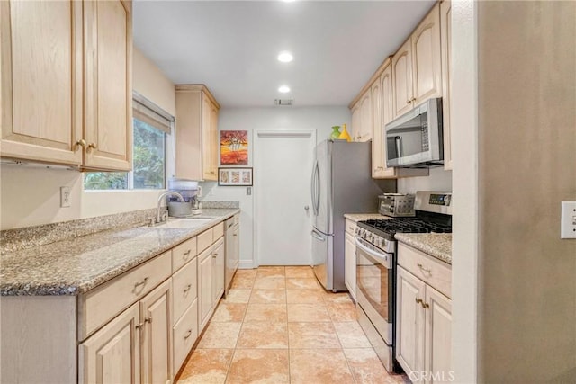 kitchen featuring sink, light brown cabinets, light stone countertops, and appliances with stainless steel finishes