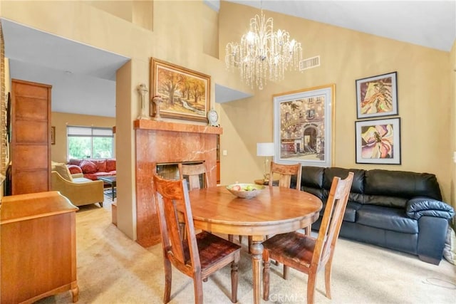 dining area with a notable chandelier, a fireplace, light carpet, and high vaulted ceiling