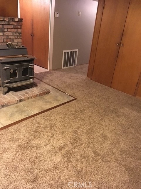 interior details featuring a wood stove, carpet, and visible vents