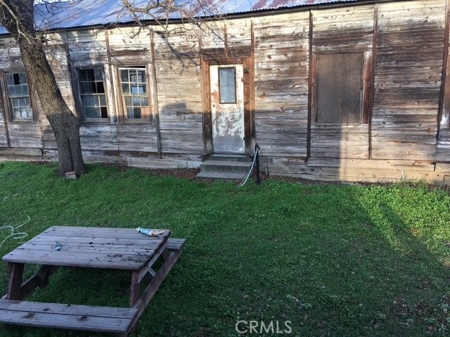 doorway to property featuring metal roof and a yard