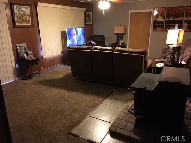 living room with carpet floors, ceiling fan, and a wood stove
