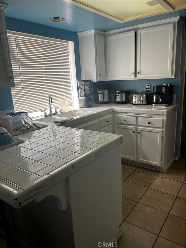 kitchen featuring tile countertops, white cabinetry, sink, and light tile patterned floors