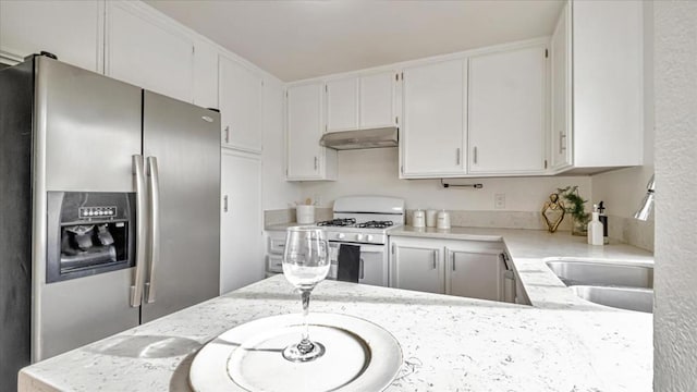 kitchen featuring white gas range, white cabinetry, stainless steel fridge with ice dispenser, and light stone counters