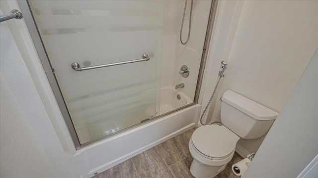 bathroom featuring hardwood / wood-style flooring, enclosed tub / shower combo, and toilet