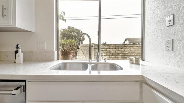 kitchen featuring light stone countertops, sink, and white cabinetry