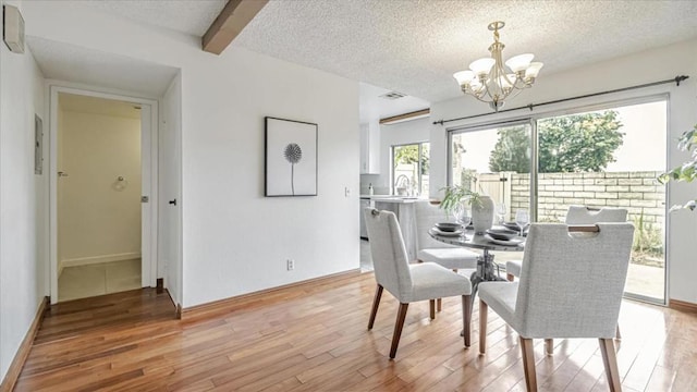 dining room featuring light wood-type flooring, a textured ceiling, beam ceiling, and an inviting chandelier