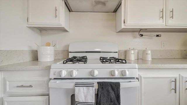 kitchen featuring light stone counters, gas range gas stove, white cabinets, and ventilation hood