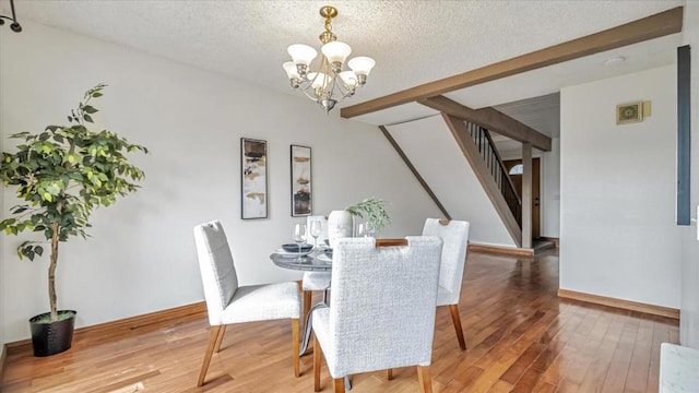 dining space with a textured ceiling, hardwood / wood-style flooring, a chandelier, and beam ceiling