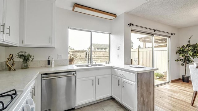 kitchen featuring a textured ceiling, dishwasher, white cabinetry, sink, and kitchen peninsula