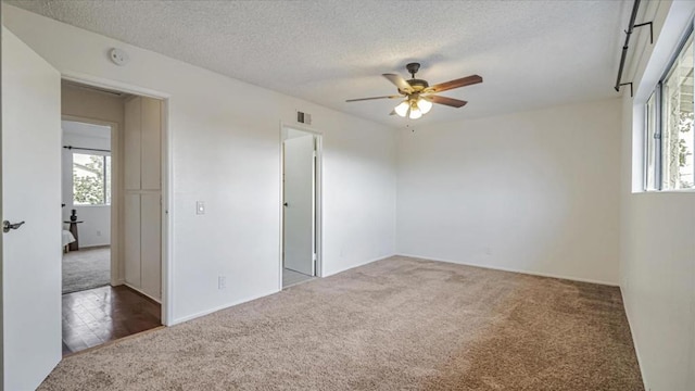 spare room featuring ceiling fan, dark colored carpet, and a textured ceiling