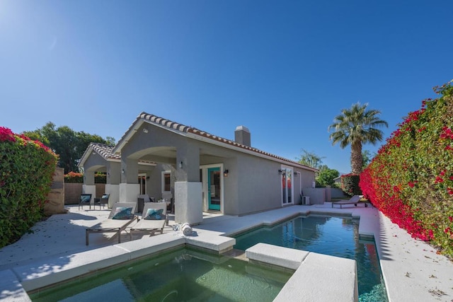 rear view of house with a fenced in pool and a patio