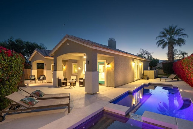 pool at dusk featuring a jacuzzi, outdoor lounge area, and a patio