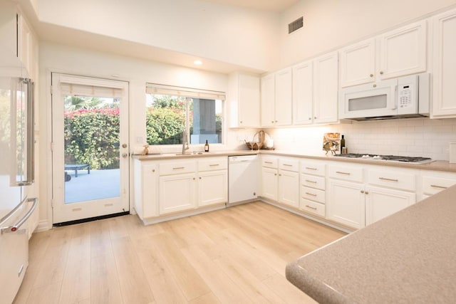 kitchen with white cabinets, white appliances, and light hardwood / wood-style flooring