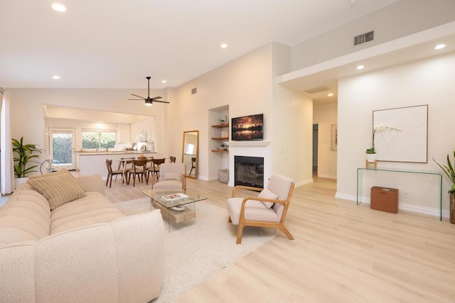 living room with ceiling fan, light hardwood / wood-style floors, and lofted ceiling