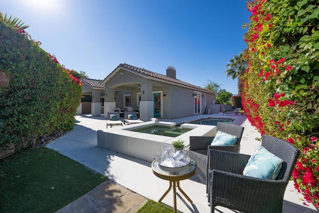 back of property featuring a patio area and a swimming pool with hot tub