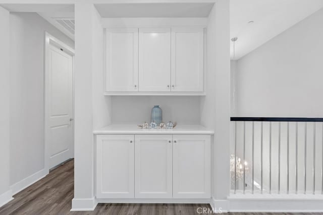 bar featuring white cabinets and dark hardwood / wood-style flooring