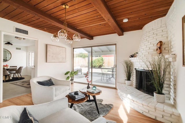 living room with beamed ceiling, wood ceiling, a fireplace, and light hardwood / wood-style flooring