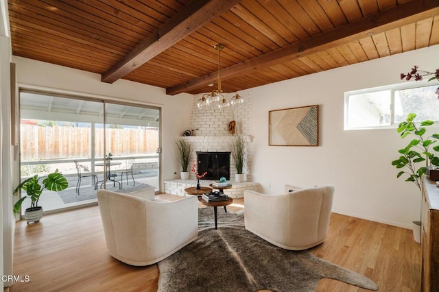 living room featuring light wood-type flooring, a brick fireplace, wood ceiling, beam ceiling, and a notable chandelier