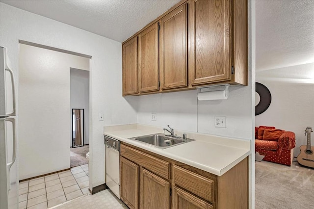 kitchen featuring a textured ceiling, white dishwasher, light colored carpet, sink, and stainless steel refrigerator