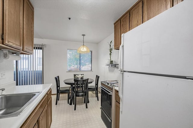 kitchen featuring sink, white refrigerator, stove, and hanging light fixtures