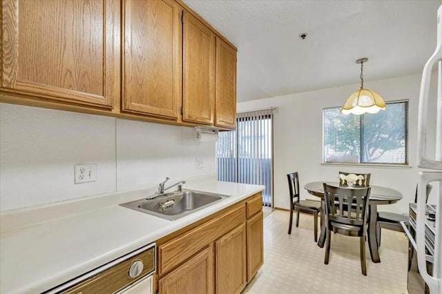 kitchen with pendant lighting, white refrigerator, stainless steel dishwasher, and sink