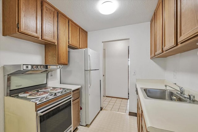 kitchen featuring electric range, sink, white fridge, and a textured ceiling