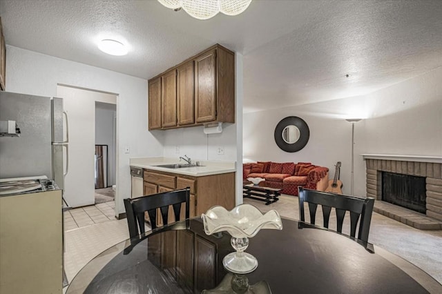 tiled dining space featuring a fireplace, a textured ceiling, and sink