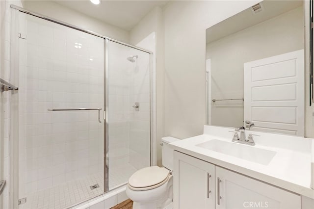 bathroom featuring vanity, toilet, and a shower with door