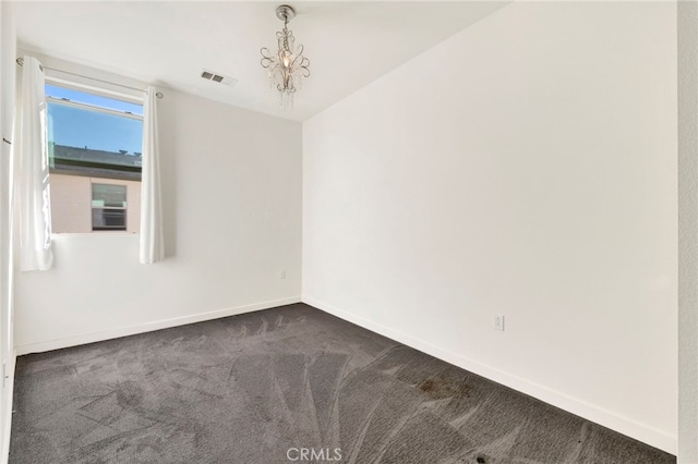 carpeted empty room with an inviting chandelier