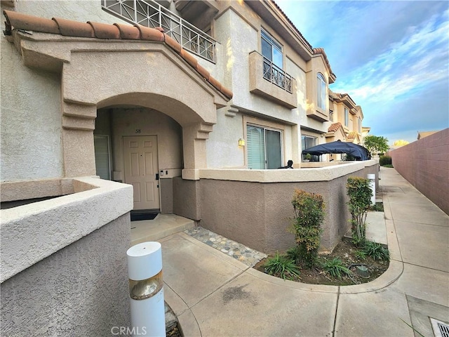 912 N Turner Ave Unit 58, Ontario, CA 91764 - view of exterior entry with a balcony, stucco siding, and fence