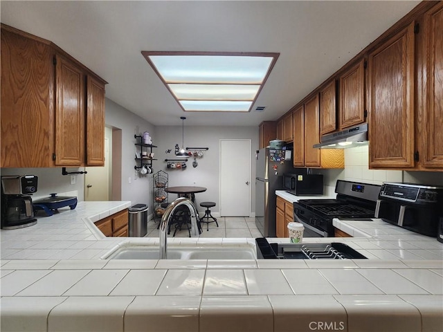 912 N Turner Ave Unit 58, Ontario, CA 91764 - kitchen featuring a sink, brown cabinets, stainless steel range with gas stovetop, under cabinet range hood, and tile countertops