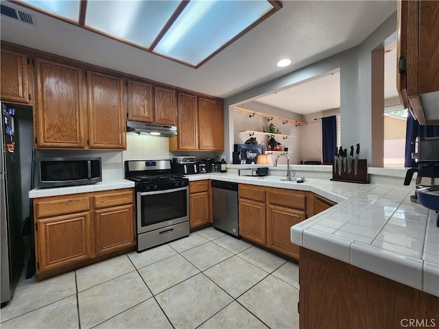 912 N Turner Ave Unit 58, Ontario, CA 91764 - kitchen featuring tile counters, appliances with stainless steel finishes, under cabinet range hood, and visible vents