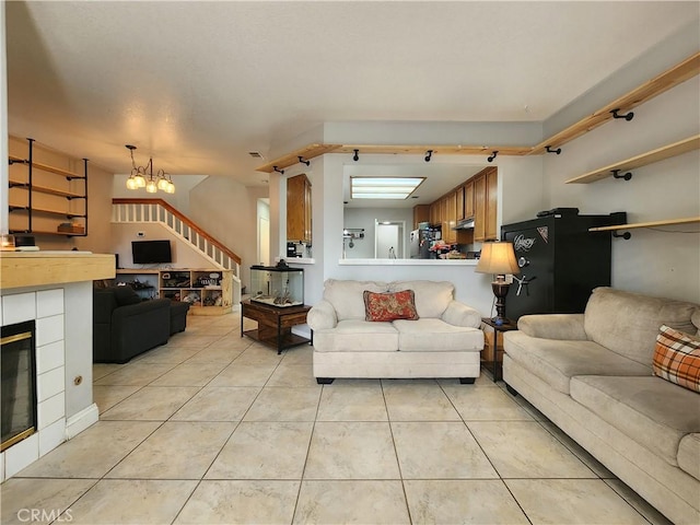 912 N Turner Ave Unit 58, Ontario, CA 91764 - living area with visible vents, a tiled fireplace, stairway, an inviting chandelier, and light tile patterned floors