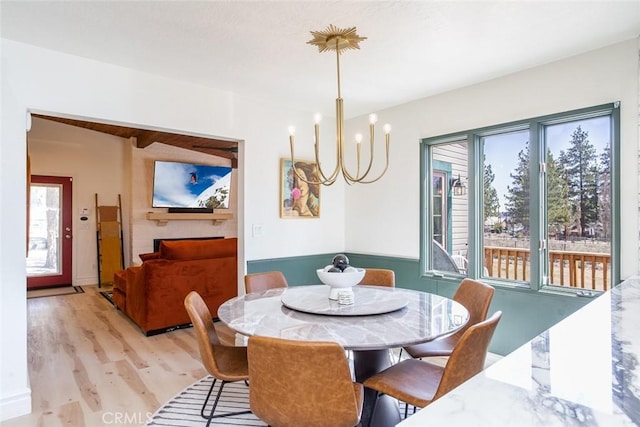 dining room with light wood-type flooring, plenty of natural light, and a notable chandelier